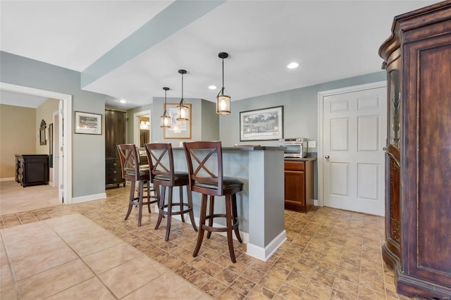 kitchen featuring a center island, dark countertops, recessed lighting, hanging light fixtures, and a kitchen bar