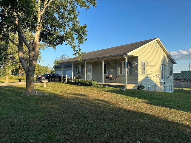 rear view of property with a yard, a garage, and covered porch