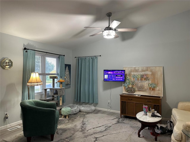 living area with visible vents, a ceiling fan, wood finished floors, baseboards, and vaulted ceiling