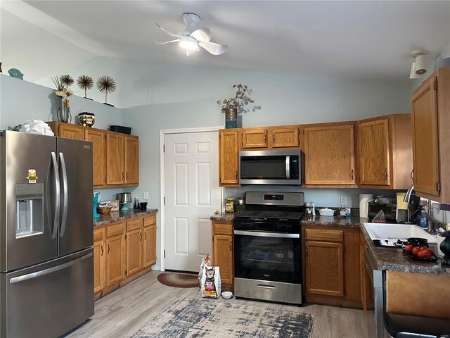 kitchen with appliances with stainless steel finishes, vaulted ceiling, ceiling fan, light hardwood / wood-style flooring, and sink