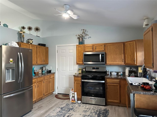kitchen with vaulted ceiling, light wood-style flooring, dark countertops, and stainless steel appliances