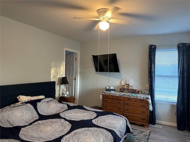bedroom featuring ceiling fan, visible vents, baseboards, and light wood-style flooring
