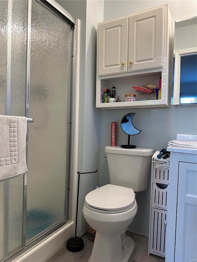 bathroom featuring vanity, a shower with shower door, and toilet