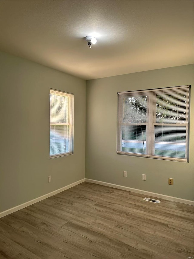 empty room with visible vents, baseboards, and wood finished floors