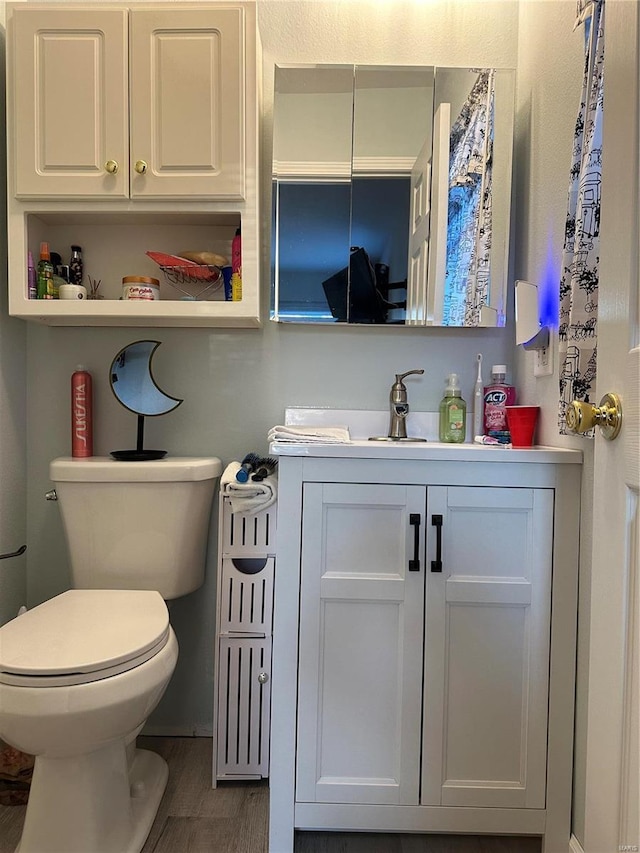 bathroom featuring toilet, wood finished floors, and vanity