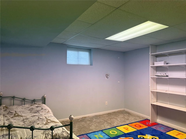carpeted bedroom featuring a drop ceiling and baseboards