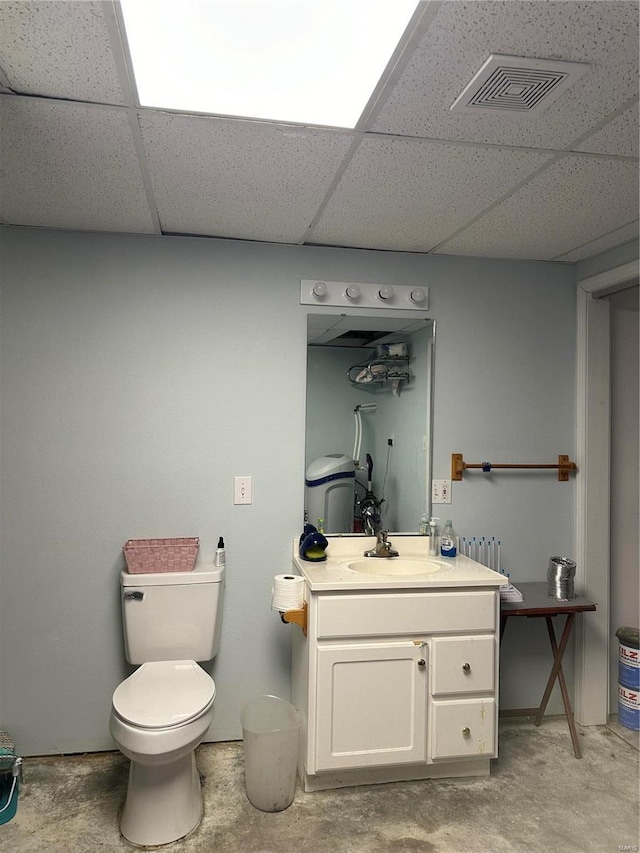 half bathroom with a drop ceiling, visible vents, unfinished concrete flooring, and vanity