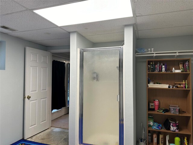 bathroom with a shower with shower door and a paneled ceiling