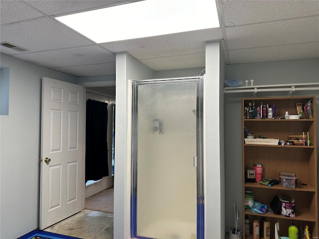 full bathroom featuring visible vents, a paneled ceiling, concrete floors, and a shower stall