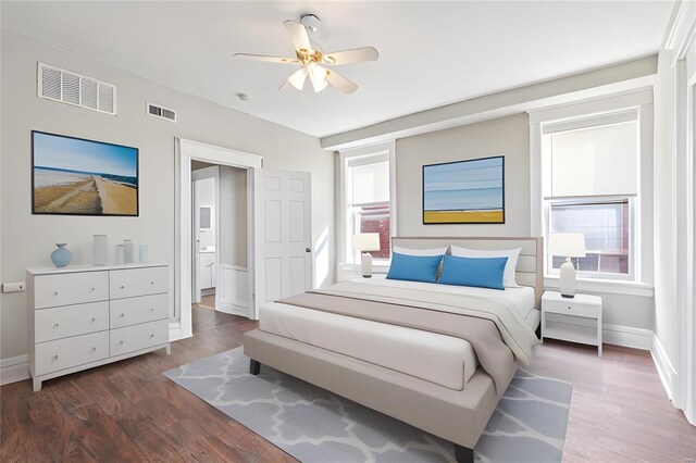 bedroom featuring ceiling fan, multiple windows, and dark hardwood / wood-style flooring