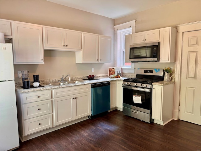 kitchen with appliances with stainless steel finishes, dark hardwood / wood-style floors, white cabinets, and sink