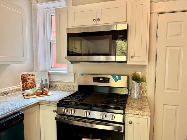 kitchen with white cabinetry, light stone counters, and appliances with stainless steel finishes