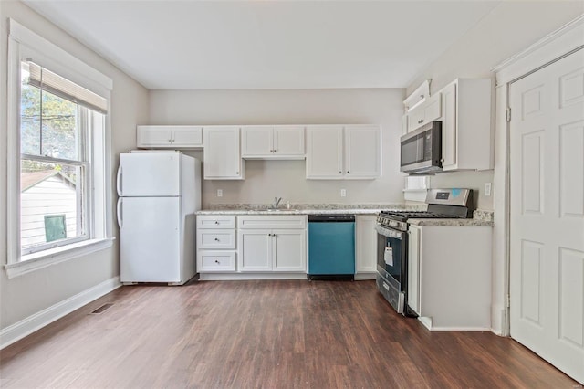 kitchen with light stone counters, appliances with stainless steel finishes, dark hardwood / wood-style floors, and white cabinets