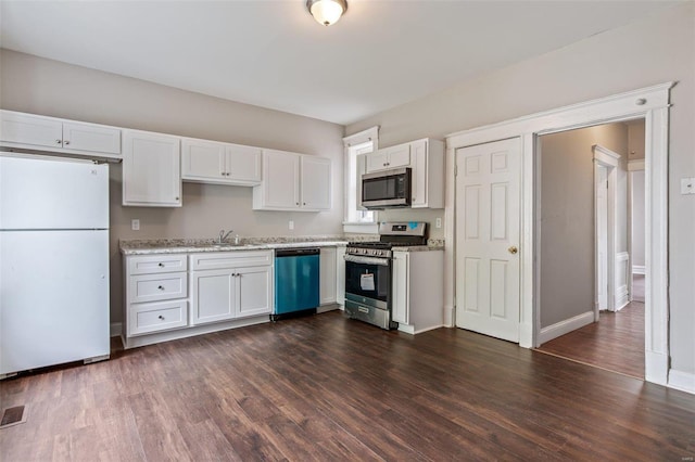 kitchen with white cabinets, light stone counters, dark hardwood / wood-style flooring, sink, and stainless steel appliances