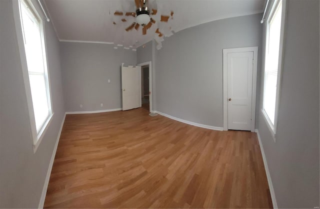 spare room featuring light wood-type flooring and vaulted ceiling