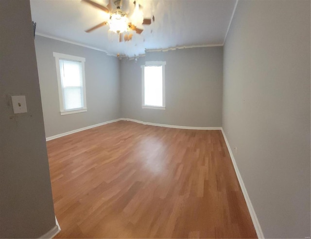 empty room with crown molding, hardwood / wood-style flooring, ceiling fan, and a wealth of natural light