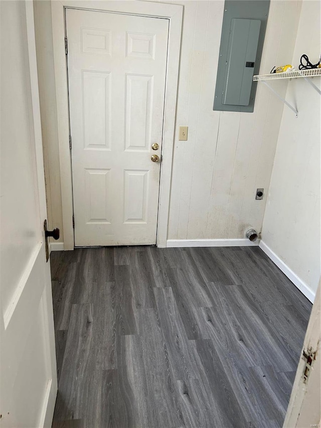 laundry room featuring dark wood-type flooring, electric panel, hookup for an electric dryer, and wooden walls