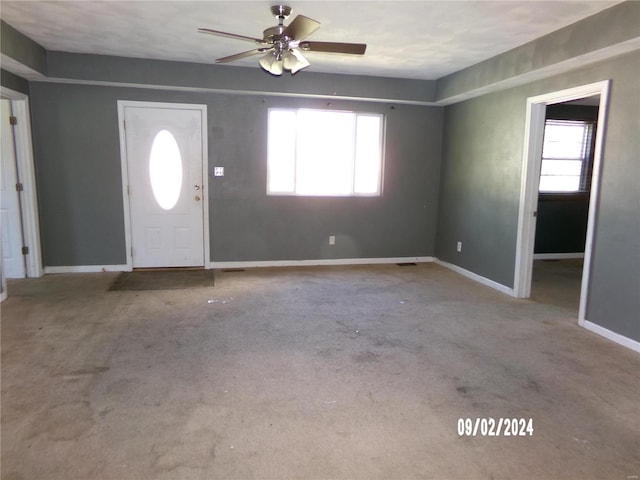 entrance foyer featuring light carpet, a wealth of natural light, and ceiling fan