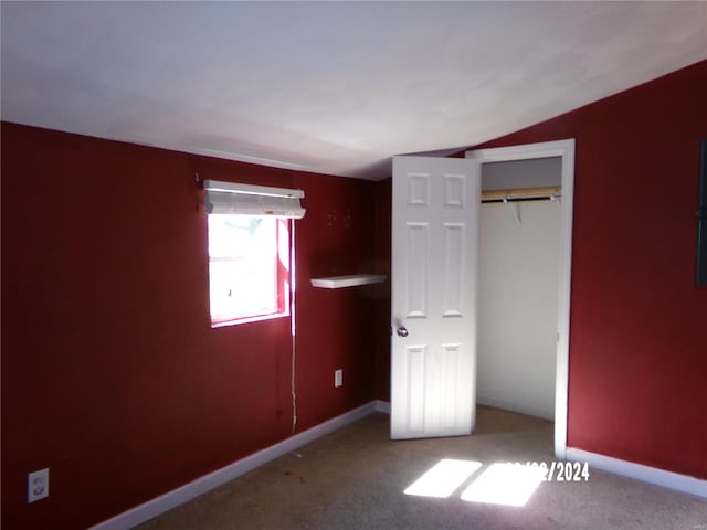 unfurnished bedroom featuring a closet, carpet, and vaulted ceiling