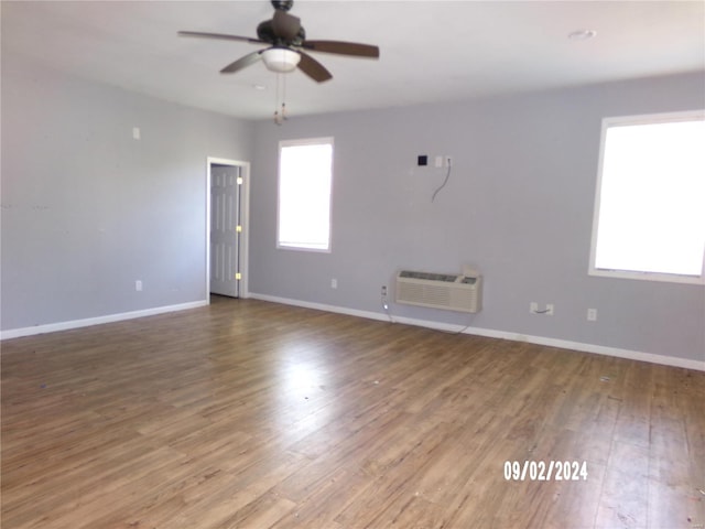 spare room featuring plenty of natural light, ceiling fan, a wall unit AC, and wood-type flooring