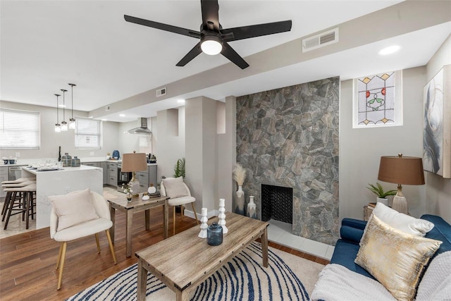 living room with a large fireplace, ceiling fan, and light hardwood / wood-style floors