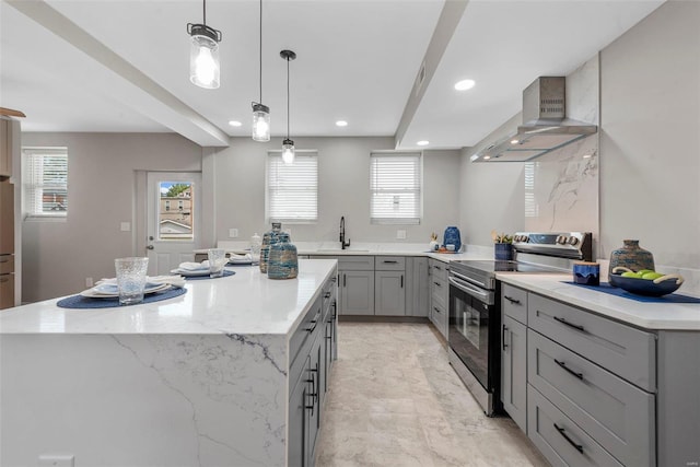 kitchen featuring gray cabinets, stainless steel range with electric cooktop, a center island, and wall chimney range hood