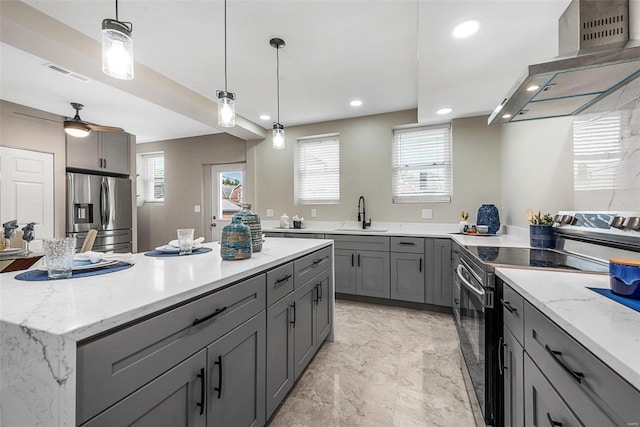 kitchen with wall chimney range hood, appliances with stainless steel finishes, a center island, and plenty of natural light