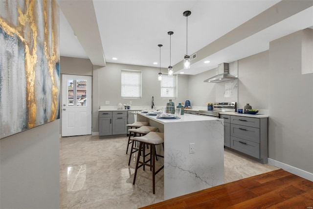 kitchen featuring wall chimney exhaust hood, a center island, a breakfast bar, electric stove, and light wood-type flooring