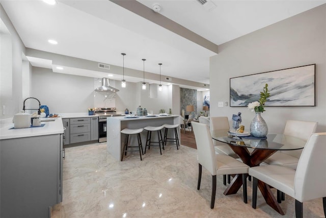 kitchen with stainless steel electric range, decorative light fixtures, sink, a breakfast bar, and wall chimney exhaust hood