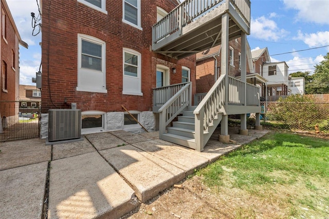 rear view of house with a balcony, a yard, a patio area, and central AC unit