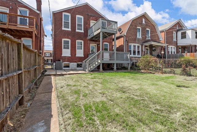 back of house with a yard, cooling unit, and a balcony