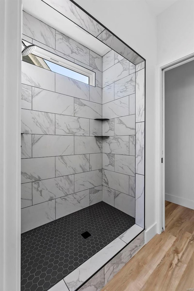 bathroom featuring a tile shower and wood-type flooring