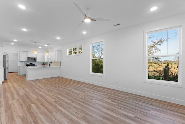 unfurnished living room with light hardwood / wood-style floors, ceiling fan, and sink