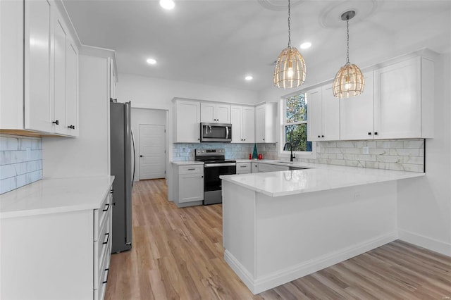 kitchen with white cabinetry, pendant lighting, stainless steel appliances, and light hardwood / wood-style floors