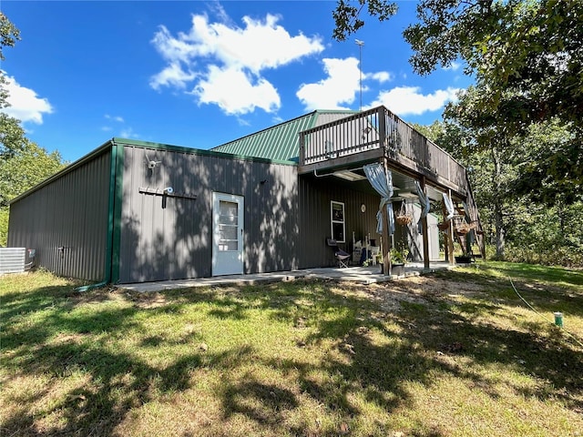 rear view of property featuring a lawn and central air condition unit