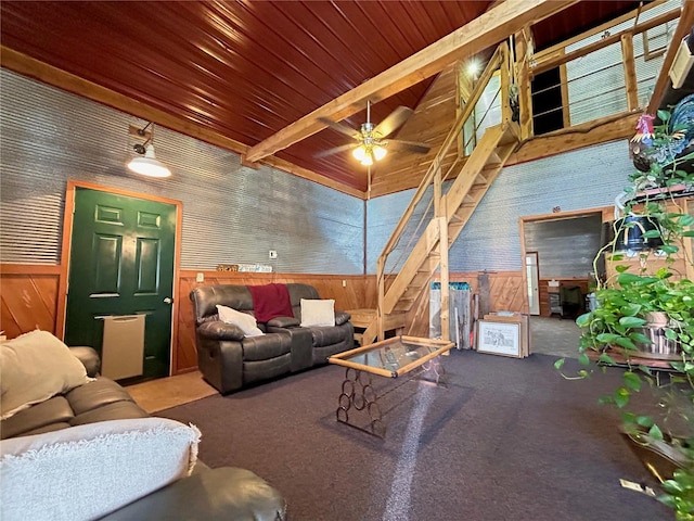 living room with carpet flooring, ceiling fan, wood walls, and beamed ceiling