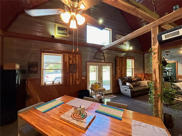 dining space featuring hardwood / wood-style flooring, wooden walls, french doors, ceiling fan, and high vaulted ceiling