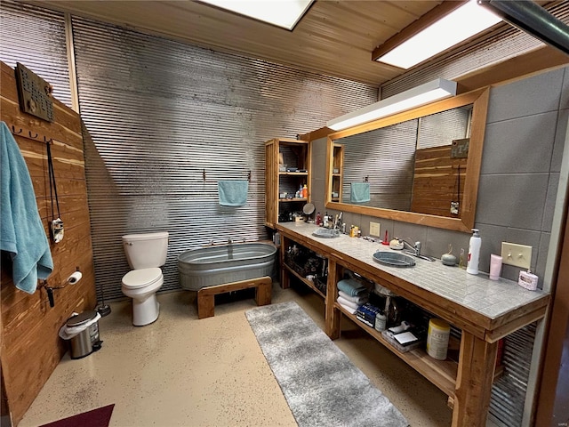 bathroom with vanity, toilet, and wood walls