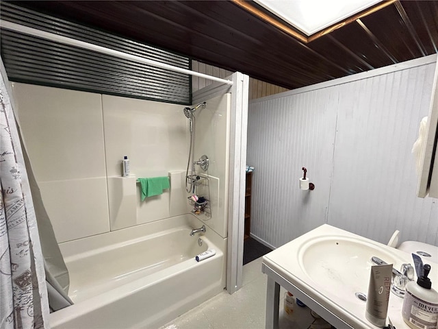 full bathroom with toilet, wooden walls, shower / tub combo with curtain, and sink