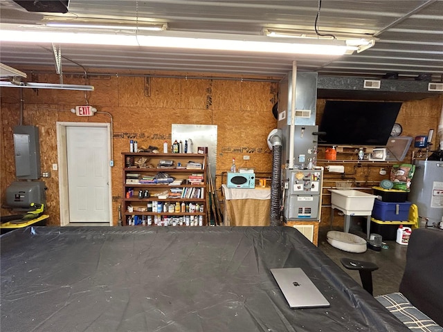 garage with gas water heater, a garage door opener, electric panel, and wooden walls