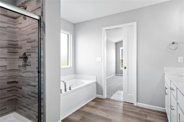 bathroom with hardwood / wood-style floors, separate shower and tub, and vanity