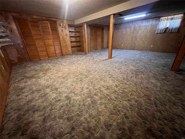 basement featuring dark carpet and wooden walls