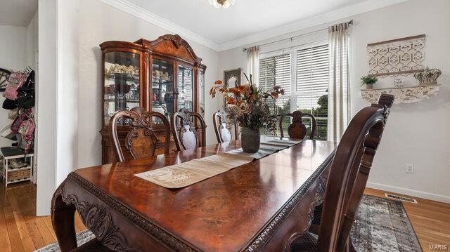 dining room with baseboards, visible vents, crown molding, and wood finished floors