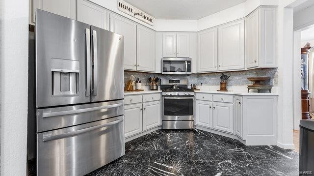 kitchen with marble finish floor, appliances with stainless steel finishes, light countertops, and backsplash