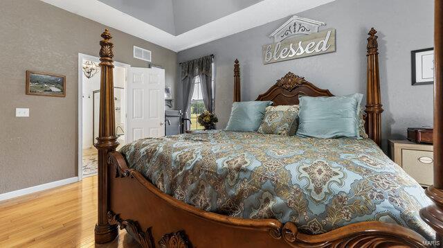 bedroom featuring baseboards, visible vents, and wood finished floors