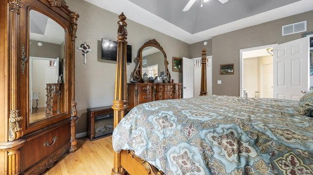 bedroom featuring lofted ceiling, ceiling fan, arched walkways, visible vents, and light wood-style floors