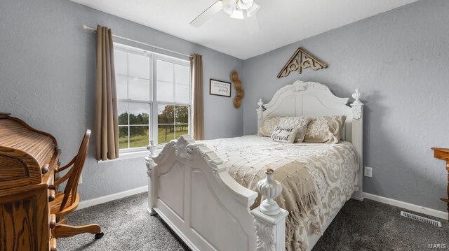 carpeted bedroom featuring a textured wall, a ceiling fan, visible vents, and baseboards