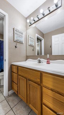 bathroom with tile patterned flooring, vanity, and toilet