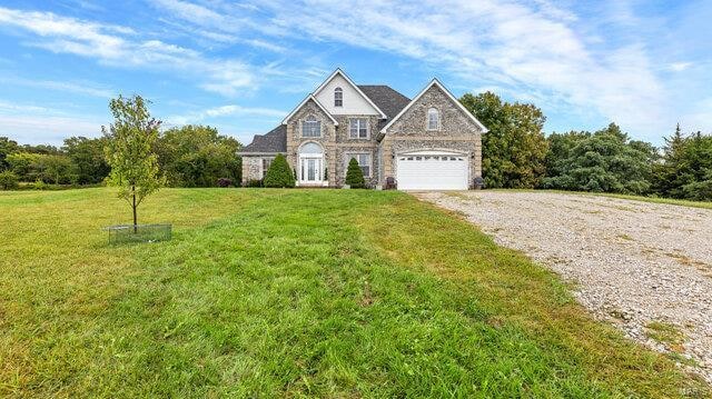 view of front of house featuring driveway, stone siding, a garage, and a front lawn