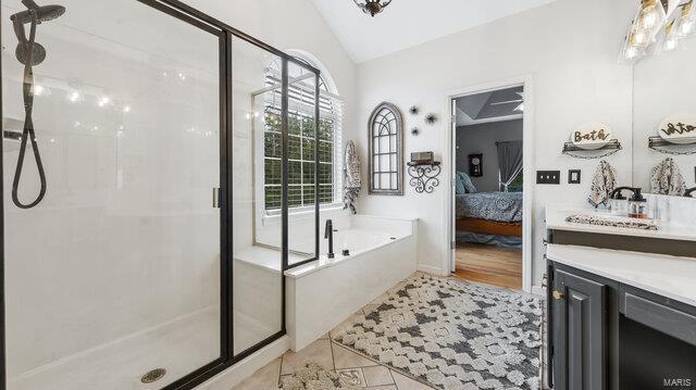 bathroom featuring shower with separate bathtub, lofted ceiling, vanity, and a wealth of natural light